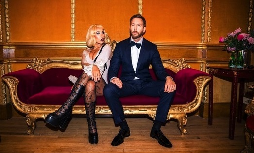Calvin Harris and eliza rose sitting on an couch